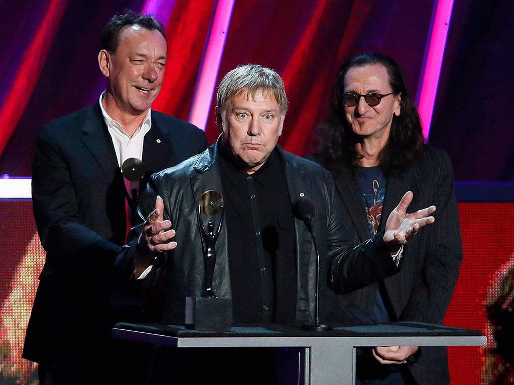 Alex Lifeson, centre, Neil Peart, left, and Geddy Lee, right, of Rush accept their band's induction into the Rock and Roll Hall of Fame at the Nokia Theatre on Thursday, April 18, 2013 in Los Angeles, Calif.