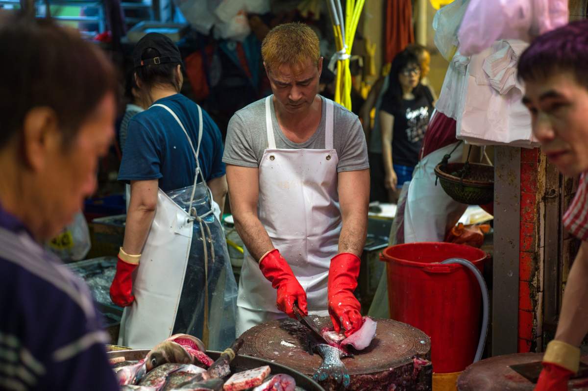 A fishmonger cuts a fish in a wet market in Hong Kong, China, 19 July 2016.
