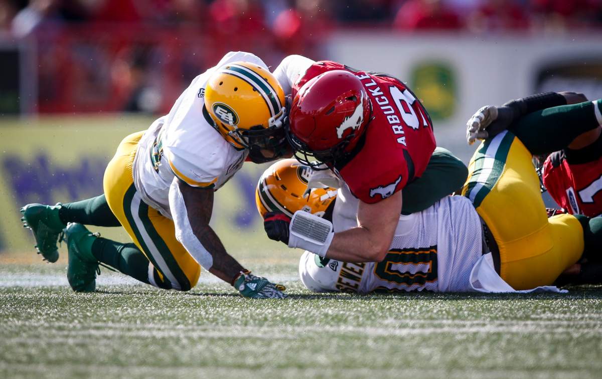 Edmonton Eskimos’ Brian Walker, left, and teammate Almondo Sewell sack Calgary Stampeders quarterback Nick Arbuckle during second half CFL football action in Calgary, Saturday, Aug. 3, 2019.