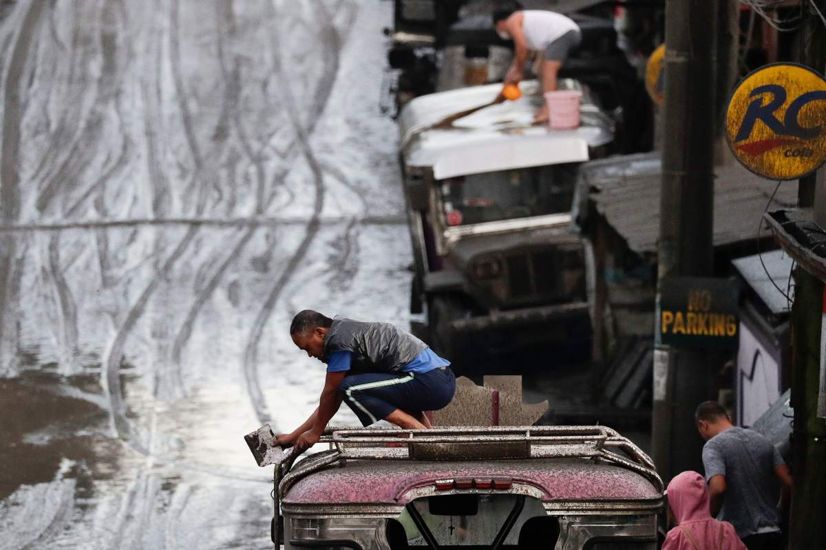 Residents clean ash from their vehicles from Taal Volcano’s eruption Monday Jan. 13, 2020, in Tagaytay, Cavite province, south of Manila, Philippines.