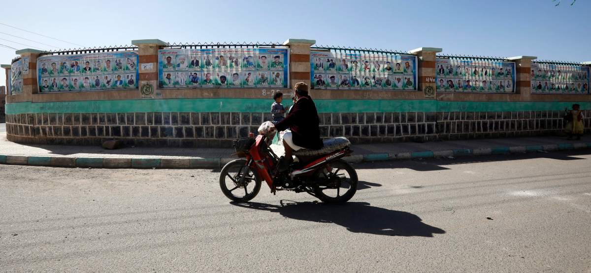 A motorcyclist drives past a wall with banners depicting portraits of late Houthi fighters allegedly killed in Yemen's ongoing conflict, in Sanaa, Yemen, 18 January 2020.   