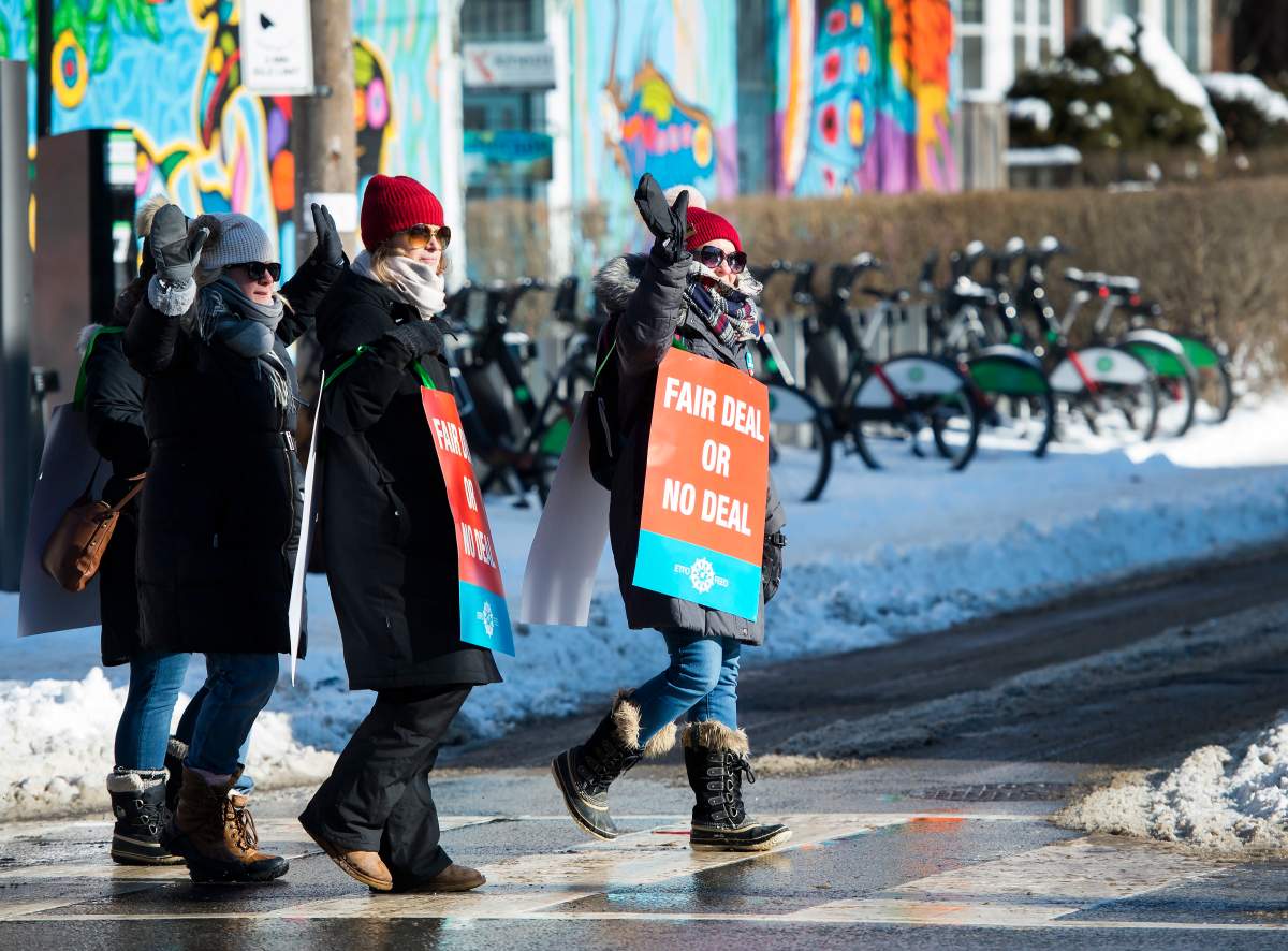 Teachers of the Elementary Teachers' Federation of Ontario wave to honking cars as they participate in a full withdrawal of services strike in Toronto on Monday, January 20, 2020. 