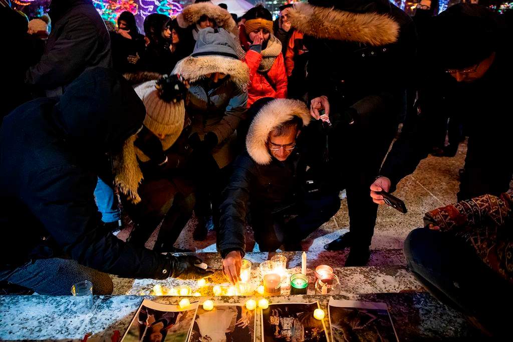 Mourners place candles and photographs during a vigil outside the Alberta Legislature Building in Edmonton on Wednesday, Jan. 8, 2020.