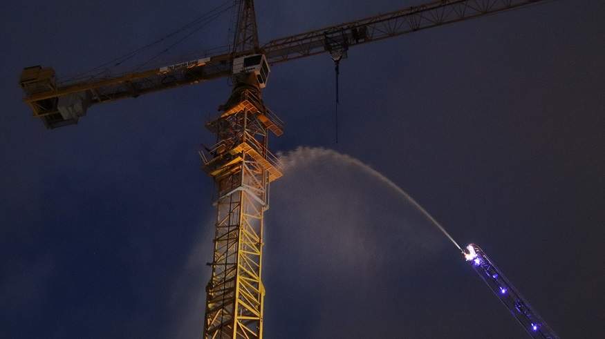 Fire crews use an aerial ladder to direct water streams at a construction crane cabin that caught fire in Coquitlam on Jan. 29, 2020.