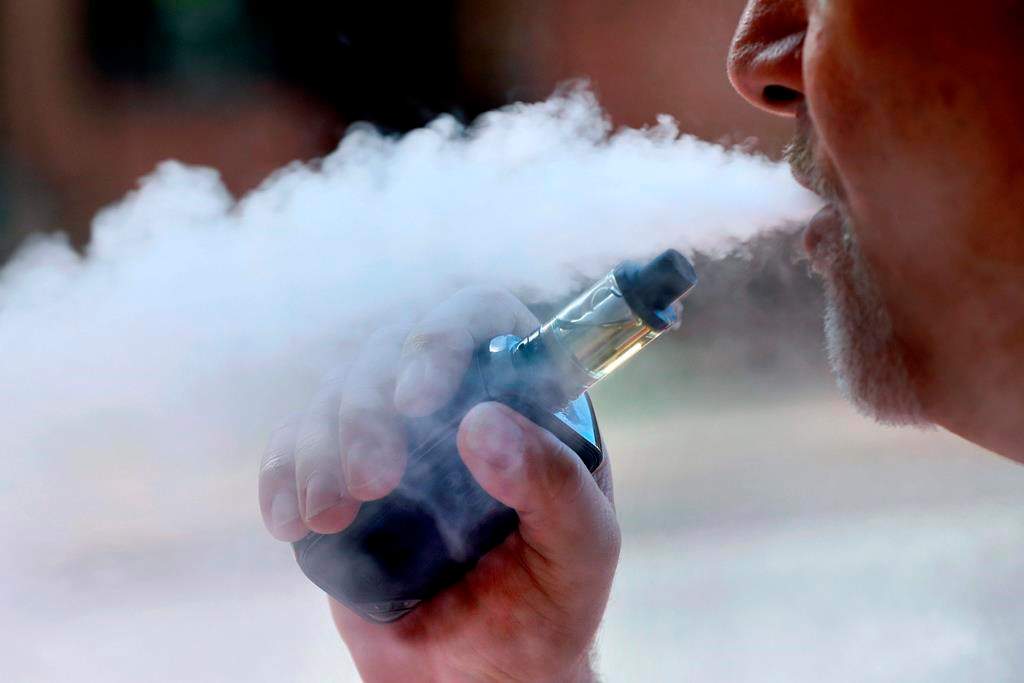 A photo of a man exhaling while vaping.