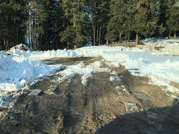 A photo showing muddy machinery tracks over headstones and burial plots at a graveyard in Enderby, B.C.