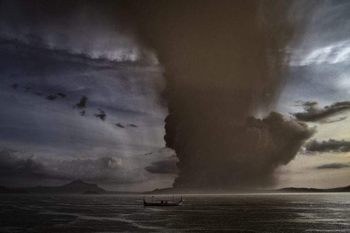A fishing boat sails along a lake as Taal Volcano erupts on Jan. 12, 2020 in Talisay, Batangas province, Philippines.