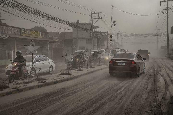 Motorists drive through a road covered in volcanic ash from Taal Volcano’s eruption on Jan. 13, 2020 in Lemery, Batangas province, Philippines.