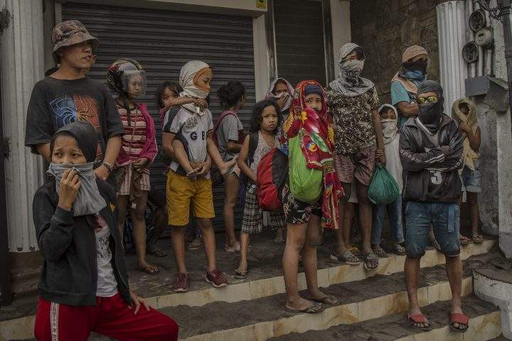 Residents fleeing Taal Volcano’s eruption wait for a ride on the side of a highway on Jan. 13, 2020 in Lemery, Batangas province, Philippines.