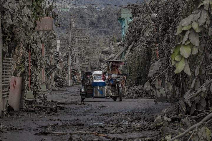 A tricycle drives along a road covered in volcanic ash from Taal Volcano’s eruption on Jan. 14, 2020 in Talisay, Batangas province, Philippines.