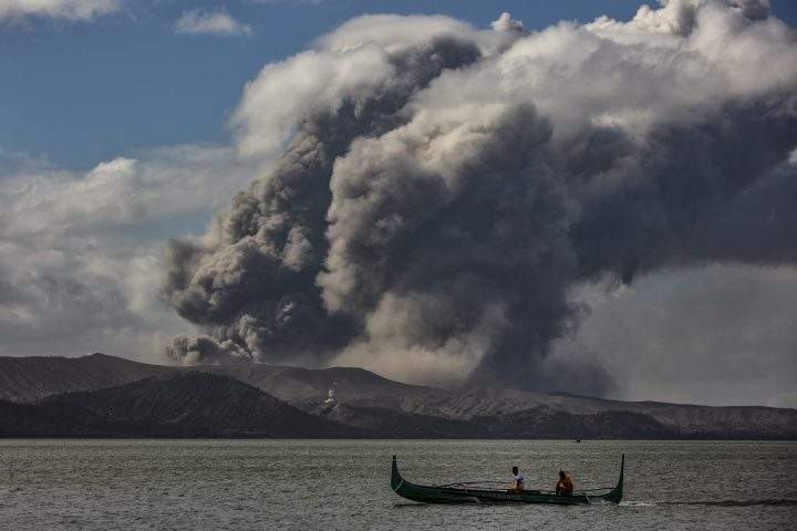 A fishing boat sails along a lake as Taal Volcano erupts on Jan. 14, 2020 in Talisay, Batangas province, Philippines.