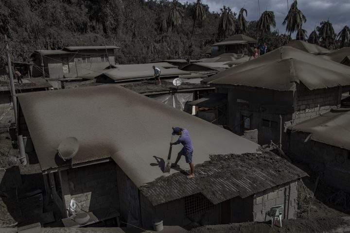 Residents clean rooftops of volcanic ash from Taal Volcano’s eruption on Jan. 14, 2020 in Laurel, Batangas province, Philippines.