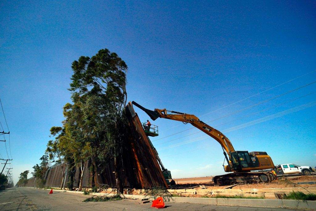 A construction crew works on a fallen section of the US-Mexico border wall as seen from Mexicali, Baja California state, Mexico, on Jan. 29, 2020. Newly installed panels from the US border wall in Calexico, Calif., fell over in high winds Wednesday, landing on trees on the Mexican side of the border.