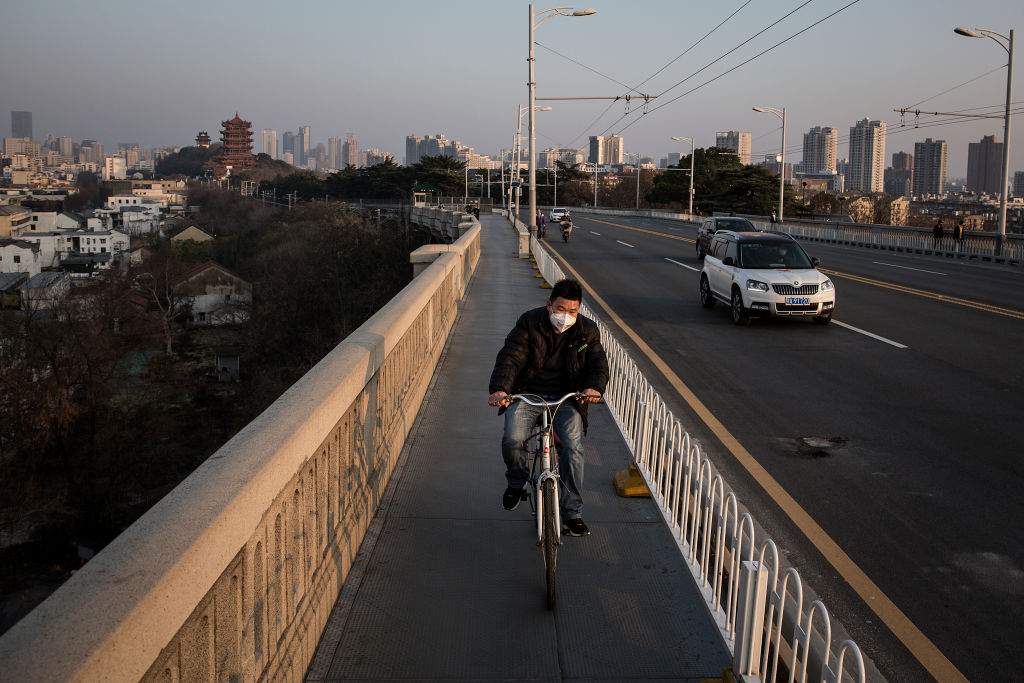 A man wears a protective mask as he rides a bicycle across the Yangtze River Bridge on Jan. 31, 2020 in Wuhan, China.