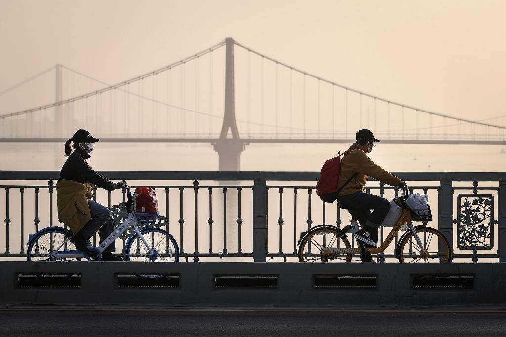 Two residents wear protective masks as they ride their bikes across the Yangtze River Bridge on Jan. 31, 2020 in Wuhan, China.