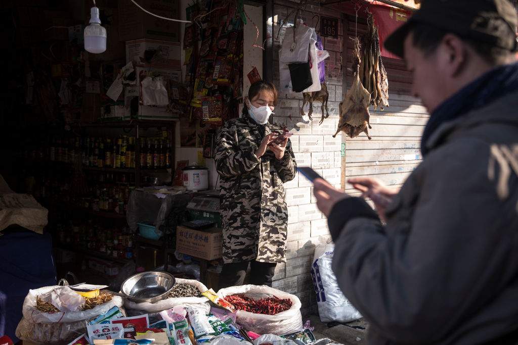 A customer uses an iPhone to pay a vendor in an alley on Jan. 31, 2020 in Wuhan, China.