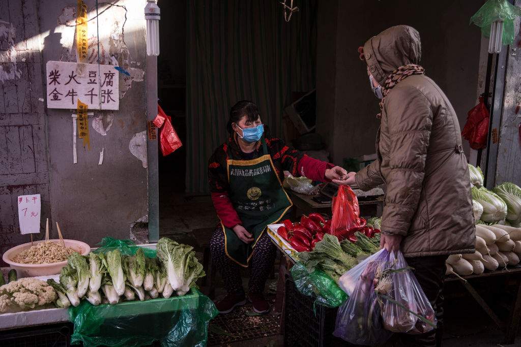 A vendor wears a protective mask as she gives change to customers in an alley on Jan. 31, 2020 in Wuhan, China.