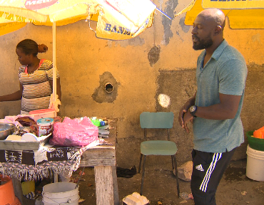 Guillano Louis walks by a vendor in Port-au-Prince.