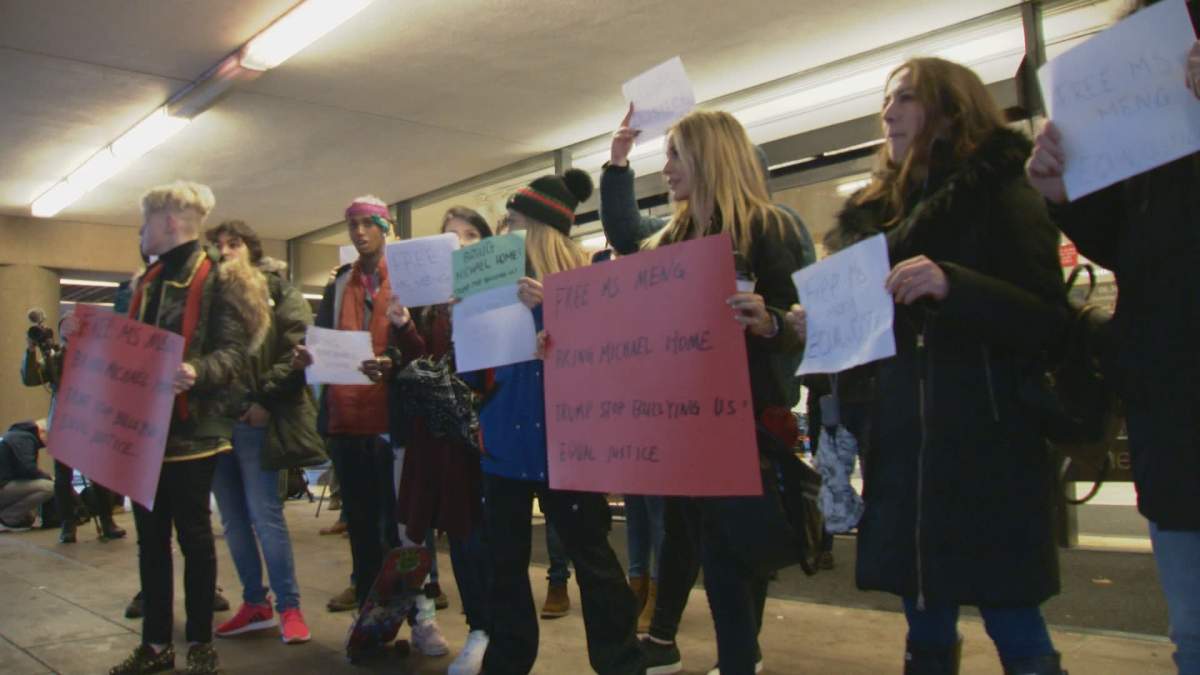 People hold signs outside an extradition trial hearing at the B.C. Supreme Court in Vancouver on Monday. 