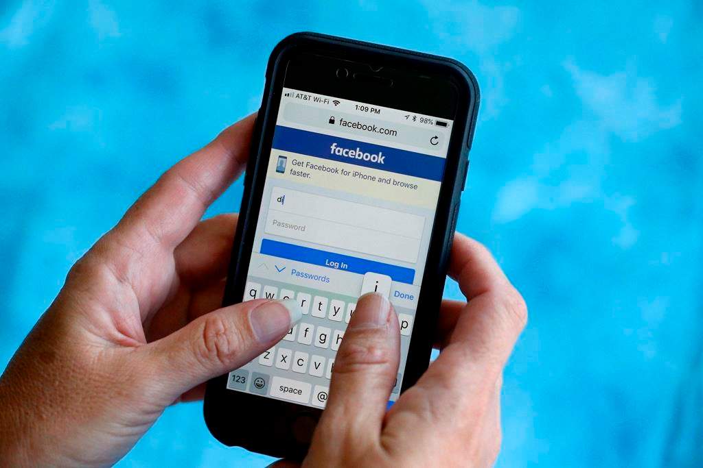 FILE - In this Aug. 21, 2018, file photo, a Facebook start page is shown on a smartphone in Surfside, Fla. Facebook says it's working to help limit the spread of misinformation and harmful content about the coronavirus and will focus on providing helpful information to people. Kang-Xing Jin, Facebook's head of health, said in a post, Friday, Jan. 31, 2020, that the social media platform's third-party fact-checkers are reviewing content and debunking false claims related to the coronavirus. (AP Photo/Wilfredo Lee, File).