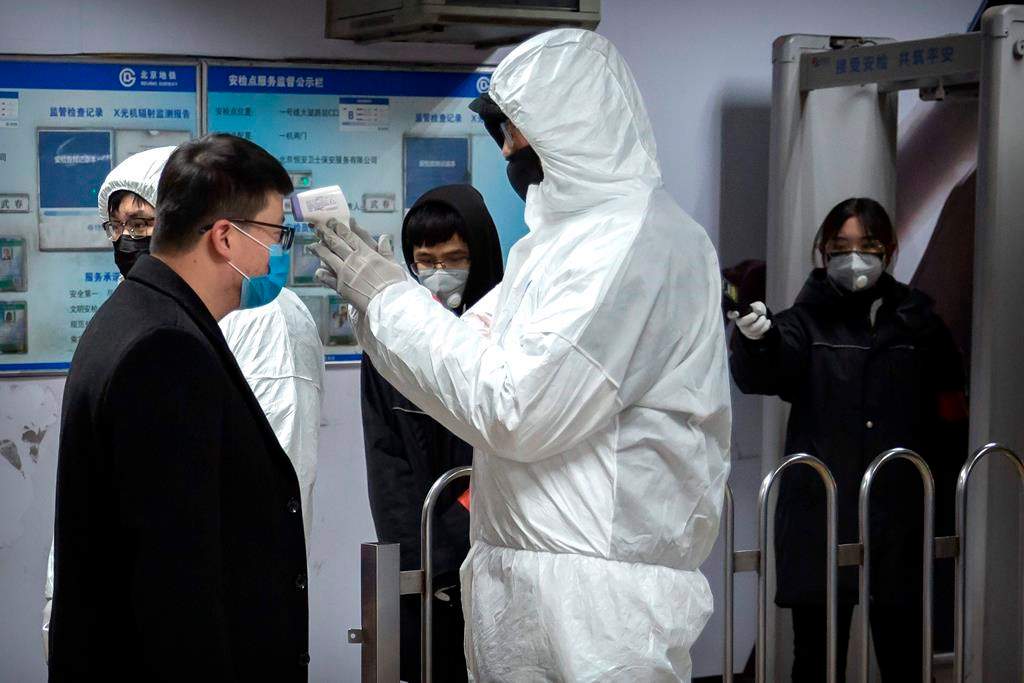 A worker wearing a hazardous materials suit takes the temperature of a passenger at the entrance to a subway station in Beijing, Sunday, Jan. 26, 2020. The new virus accelerated its spread in China, and the U.S. Consulate in the epicentre of the outbreak, the central city of Wuhan, announced Sunday it will evacuate its personnel and some private citizens aboard a charter flight.