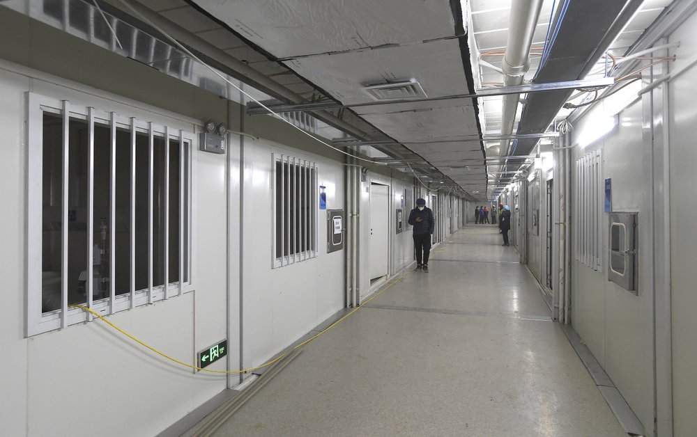 People walk down a corridor at the Huoshenshan temporary field hospital in Wuhan in central China’s Hubei Province, Sunday, Feb. 2, 2020. The Philippines on Sunday reported the first death from a new virus outside of China, where authorities delayed the opening of schools in the worst-hit province and tightened quarantine measures in a city that allow only one family member to venture out to buy supplies.