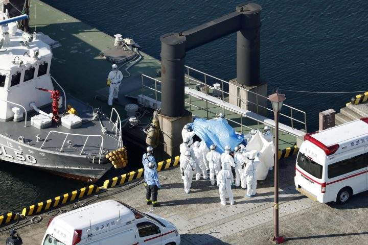 Medical workers in protective suits lead a passenger tested positive for a new coronavirus from the cruise ship Diamond Princess at Yokohama Port in Yokohama, south of Tokyo, Wednesday, Feb. 5, 2020.