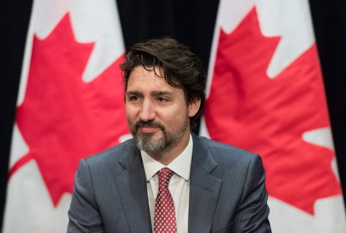 Prime Minister Justin Trudeau is framed between two Canadian flags during a meeting in Montreal, Friday, January 31, 2020. 