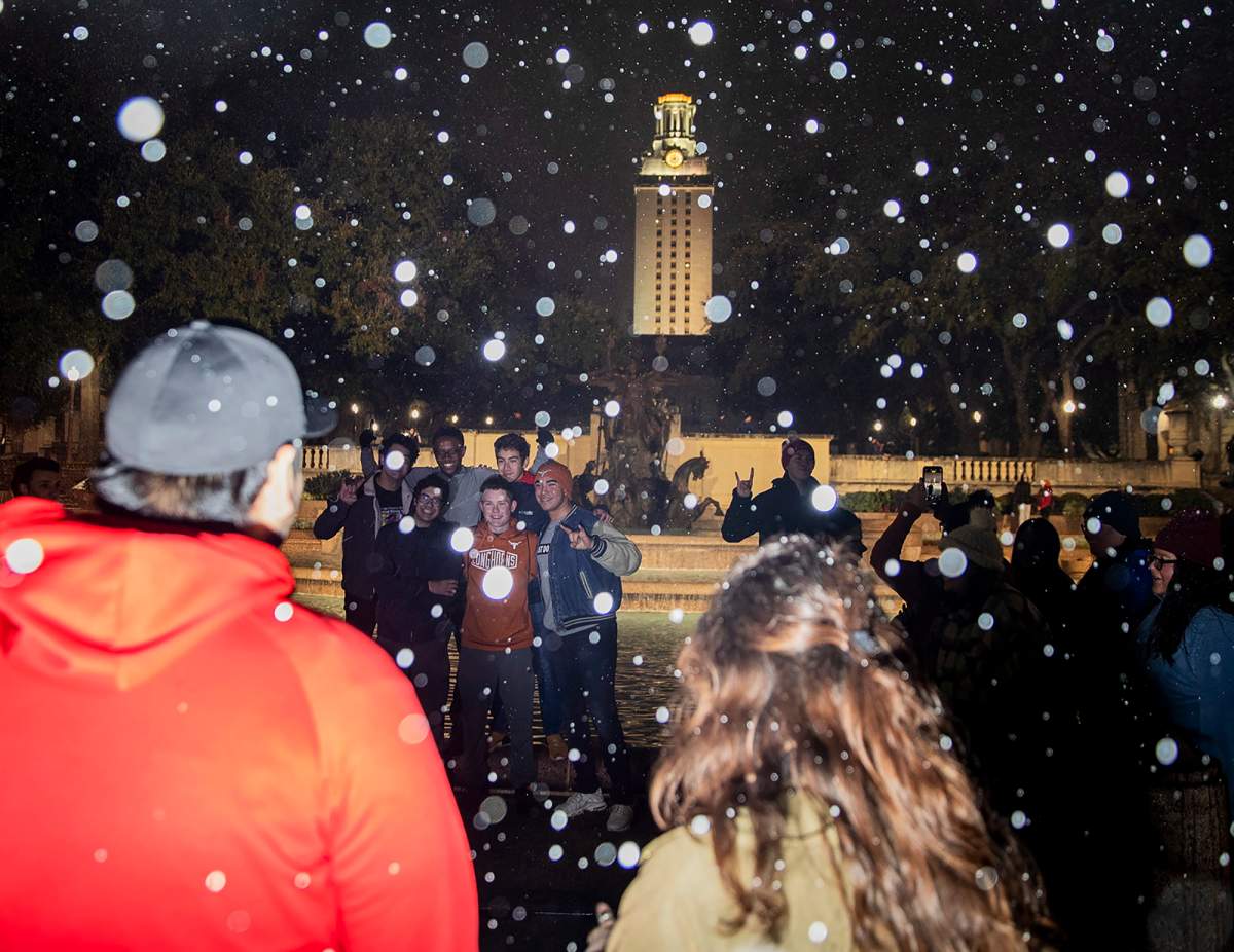 University of Texas students take pictures near the Littlefield Fountain and UT Tower as snow falls, late Feb. 5, 2020, in Austin, Texas.