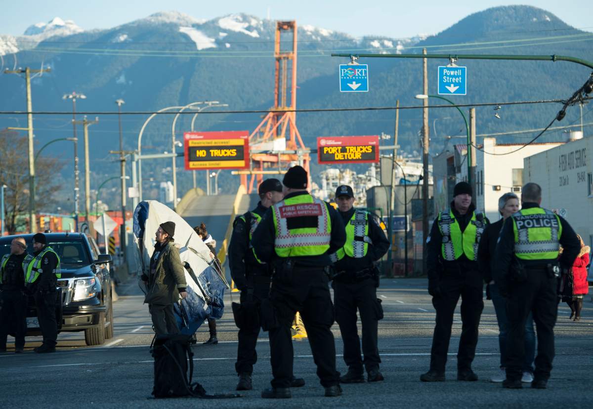 Police look on as protesters remove their tents from blocking one of the road access points to one of Vancouver’s port entrances on Monday, Feb. 10, 2020.