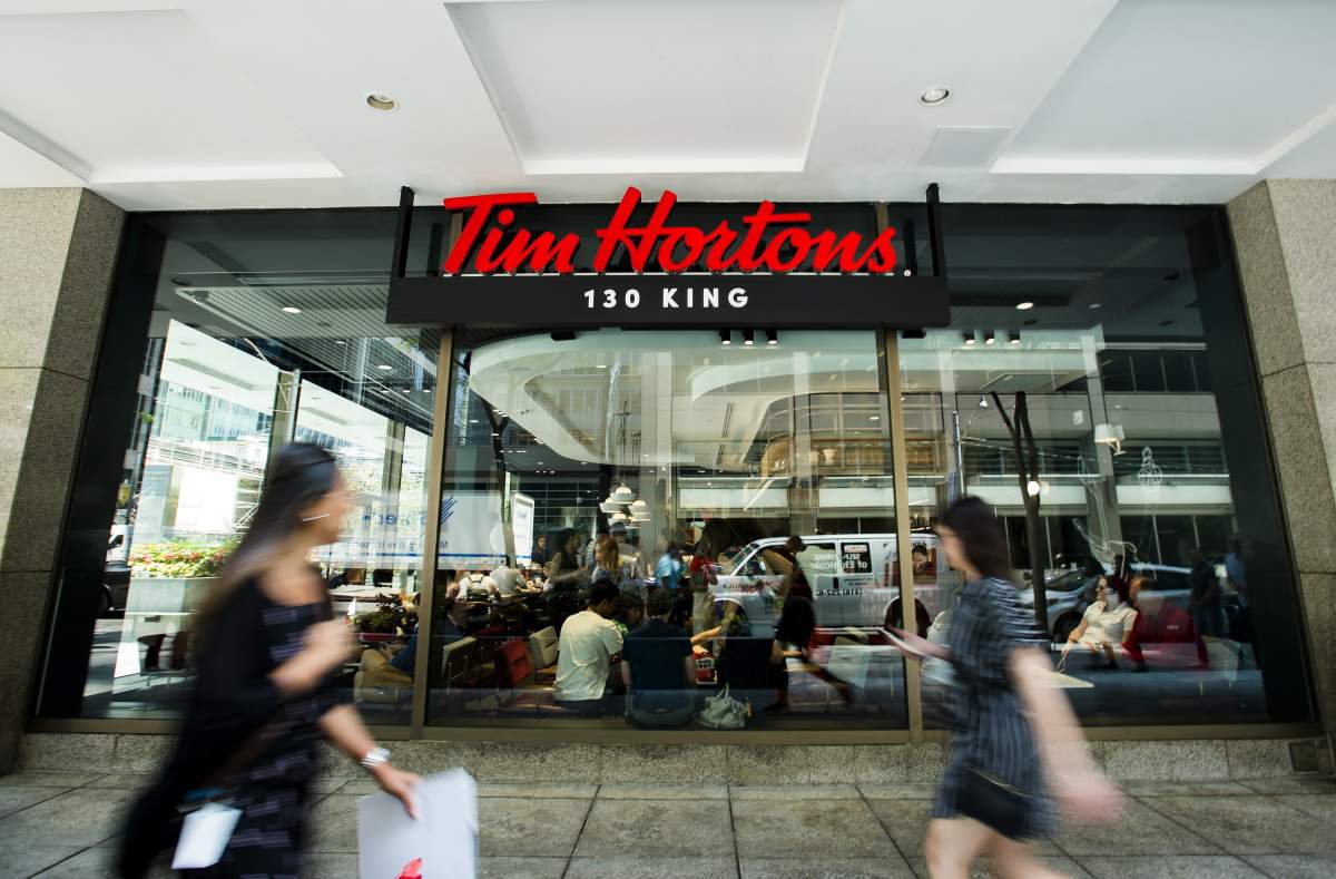 People walk past a newly renovated Tim Hortons in Toronto on Thursday, July 25, 2019.
