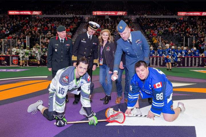 Chris Corbeil of the Saskatchewan Rush and Cody Jamieson of the Halifax Thunderbirds pose with Canadian Armed Forces officials and Jim Lowther and Debbie Lowther of VETS Canada.