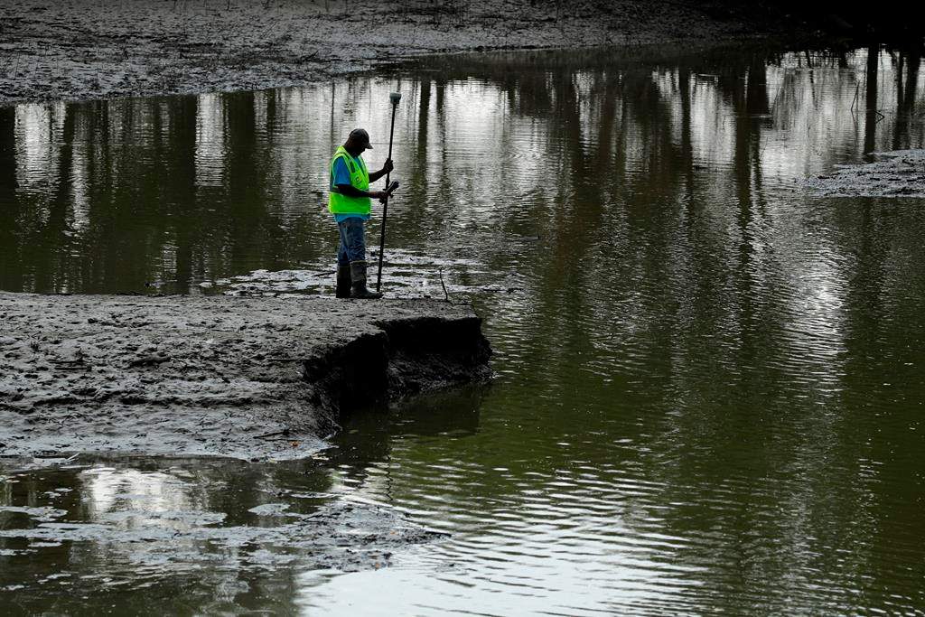 FILE - In this Aug. 6, 2019, file photo, U.S. Army Corps of Engineers worker Ron Allen uses a GPS tool to survey the extent of damage where a levee failed along the Missouri River near Saline City, Mo. The National Weather Service said Thursday, Feb. 13, 2020, there is an elevated flood risk along the eastern Missouri River basin this spring because the soil remains wet and significant snow is on the ground in North Dakota and South Dakota. (AP Photo/Charlie Riedel, File).