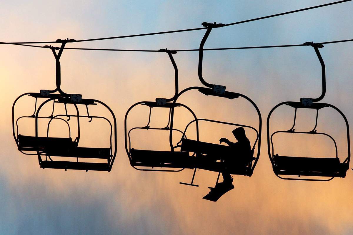 A silhouetted snowboarder makes his way up the chairlift during sunset at the Chicopee ski resort. The resort will offer camps in Kitchener over March Break,.