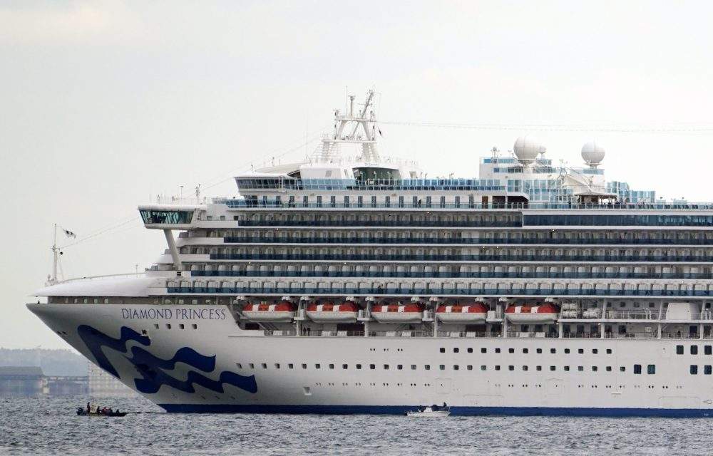 Light boats travel before the Diamond Princess cruise ship, anchored in quarantine off the port of Yokohama in Japan, Feb. 4, 2020.