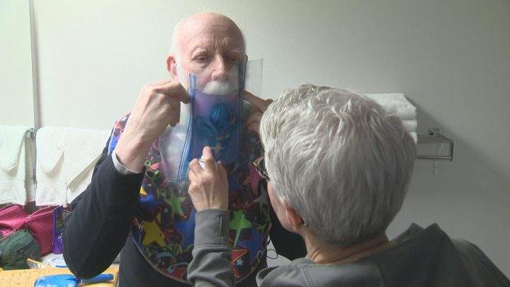 Madsen\’s wife, Judy, spray paints Team Quebec\’s fleur-de-lis logo onto his beard.