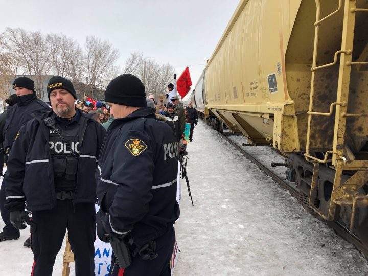 Saskatoon Police officers keep demonstrators away from the passing train.