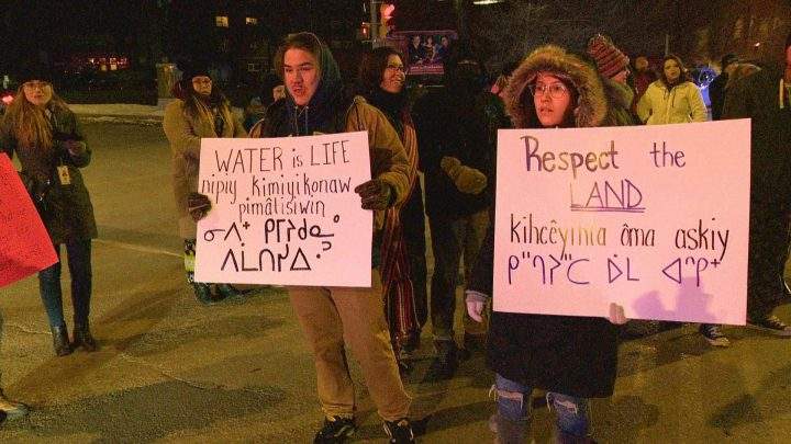 Regina protesters hold up signs reading “Water Is Life” and “Respect The Land”
