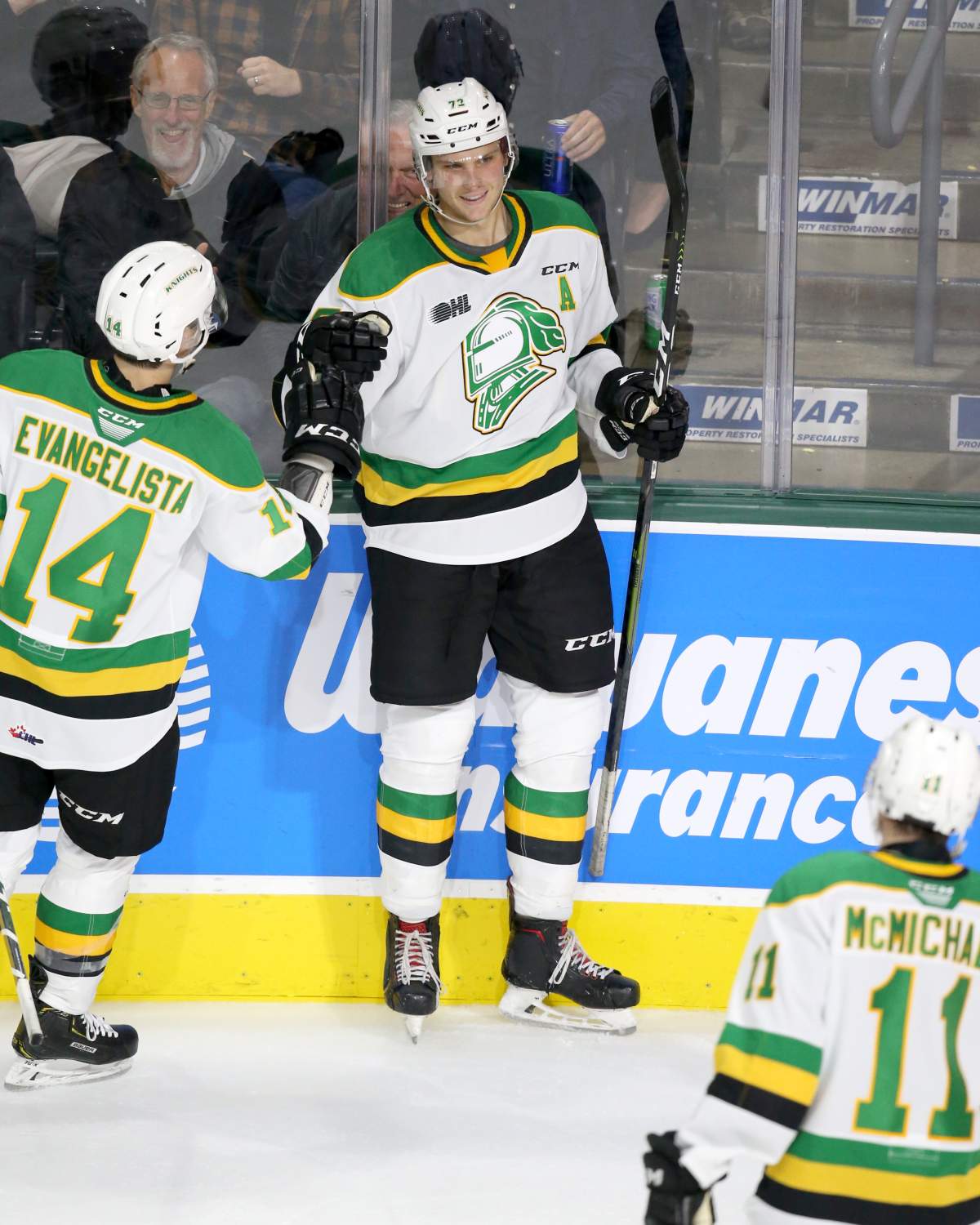 Alec Regula celebrates a power-play goal with Luke Evangelista and Connor McMichael.