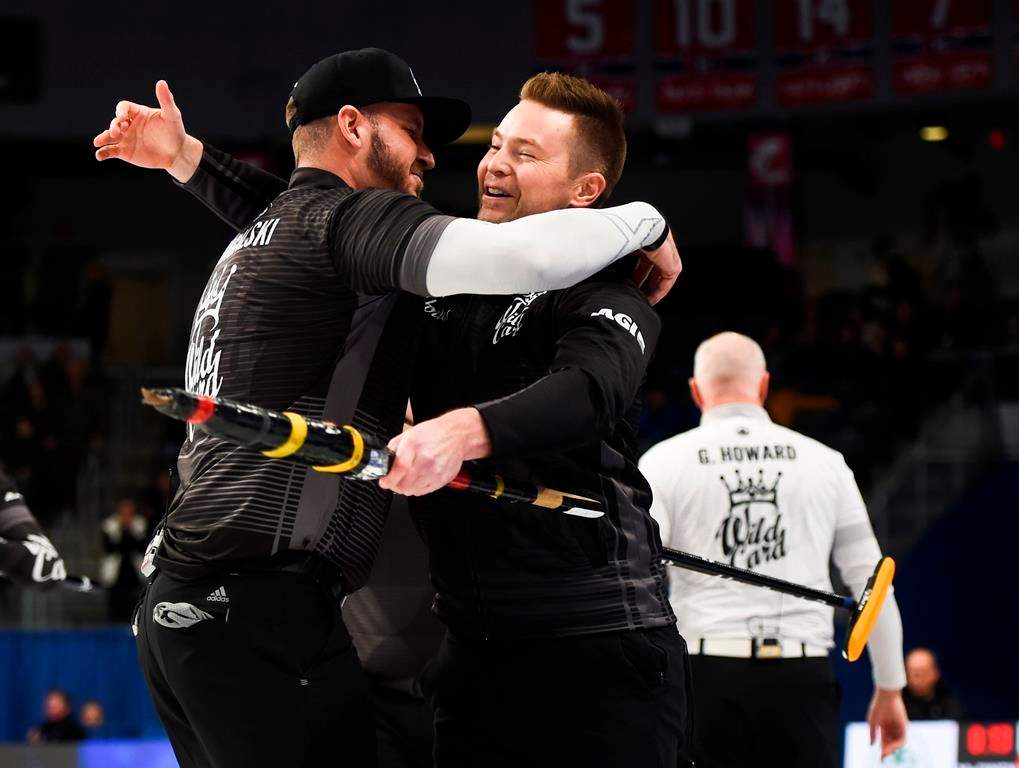 Team McEwen skip Mike McEwen, middle, celebrates his win with second Derek Samagalski as Team Howard skip Glenn Howard, right, walks off following the wild card game at the Brier in Kingston, Ont., on Friday, Feb. 28, 2020.