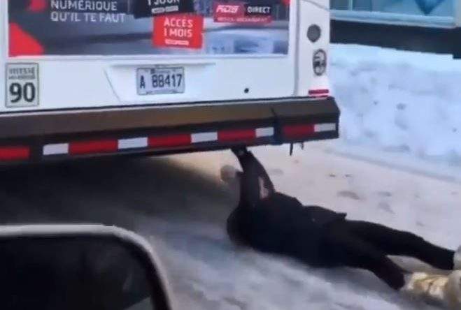 The woman is filmed gripping the bumper of the bus as it travels through downtown Montreal.