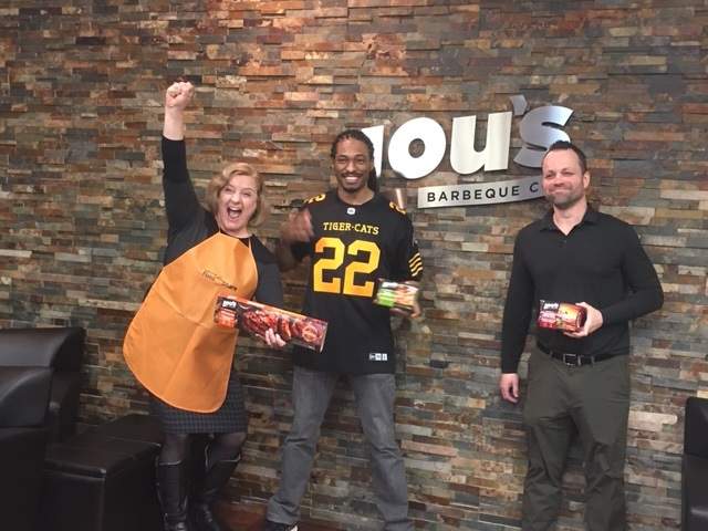 Hamilton Food Share's Celeste Taylor, Hamilton Tiger Cat defensive back Courtney Stephen and Lou's Kitchen COO Roland Love celebrate a 3,200-pound donation to local food banks.