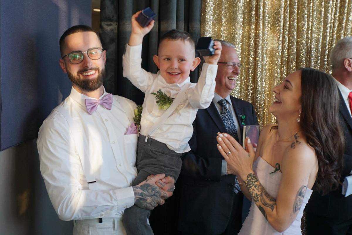 Newlyweds Lauren Hunter and Kyle Gutscher celebrate with their ring bearer after being married.