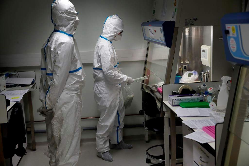 French lab scientists in hazmat gear inserting liquid in test tube manipulate potentially infected patient samples at Pasteur Institute in Paris, Thursday, Feb. 6, 2020. Scientists at the Pasteur Institute developed and shared a quick test for the new virus that is spreading worldwide, and are using genetic information about the coronavirus to develop a potential vaccine and treatments.