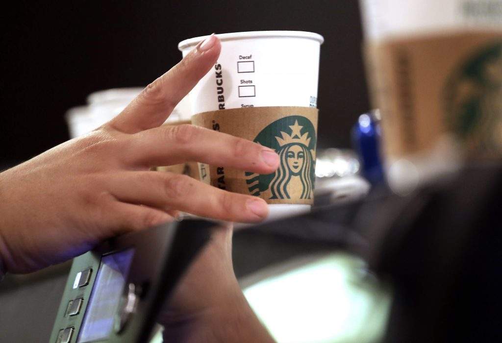 FILE- In this May 29, 2018, file photo, a barista reaches for an empty cup at a Starbucks, commonly referred to as the original Starbucks, in the Pike Place Market in Seattle. 