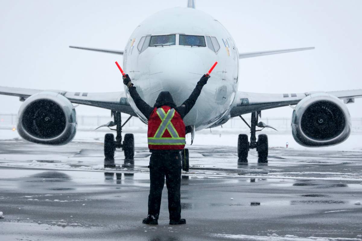 A ground crew member guides a plane into position at an airport in Calgary, Alta., Tuesday, Nov. 19, 2019.