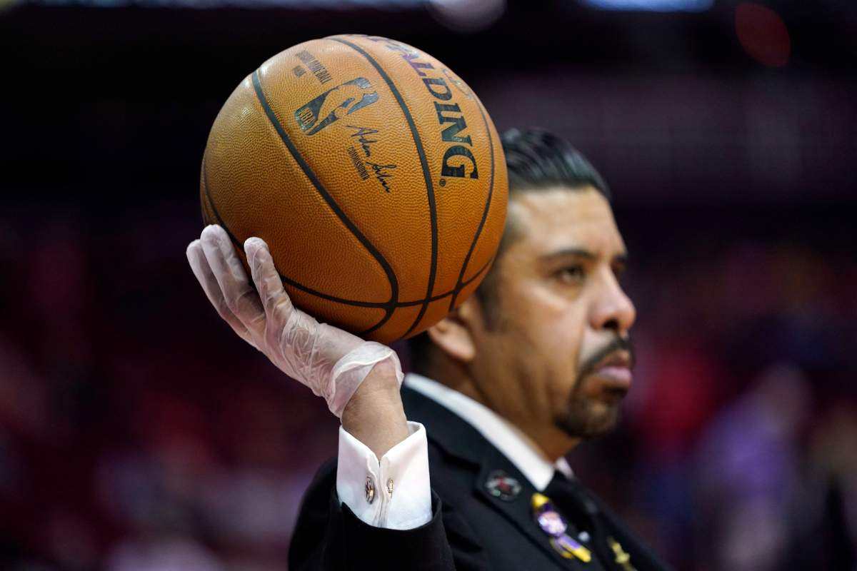 Security guard David Castillo wears gloves while holding a basketball during halftime of an NBA basketball game between the Los Angeles Clippers and Houston Rockets on Thursday, March 5, 2020 in Houston.