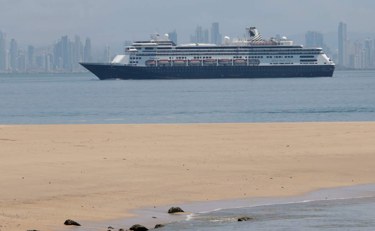 The Zaandam cruise ship, carrying dozens of guests with flu-like symptoms, arrives to the bay of Panama City, seen from Isla de Taboga, Panama, Friday, March 27, 2020, amid the worldwide spread of the new coronavirus. Once the vessel reaches Panamanian waters, health authorities are expected to board the ship to test passengers and decide whether it can cross the Panama Canal to head on towards Fort Lauderdale. (AP Photo/Arnulfo Franco).
