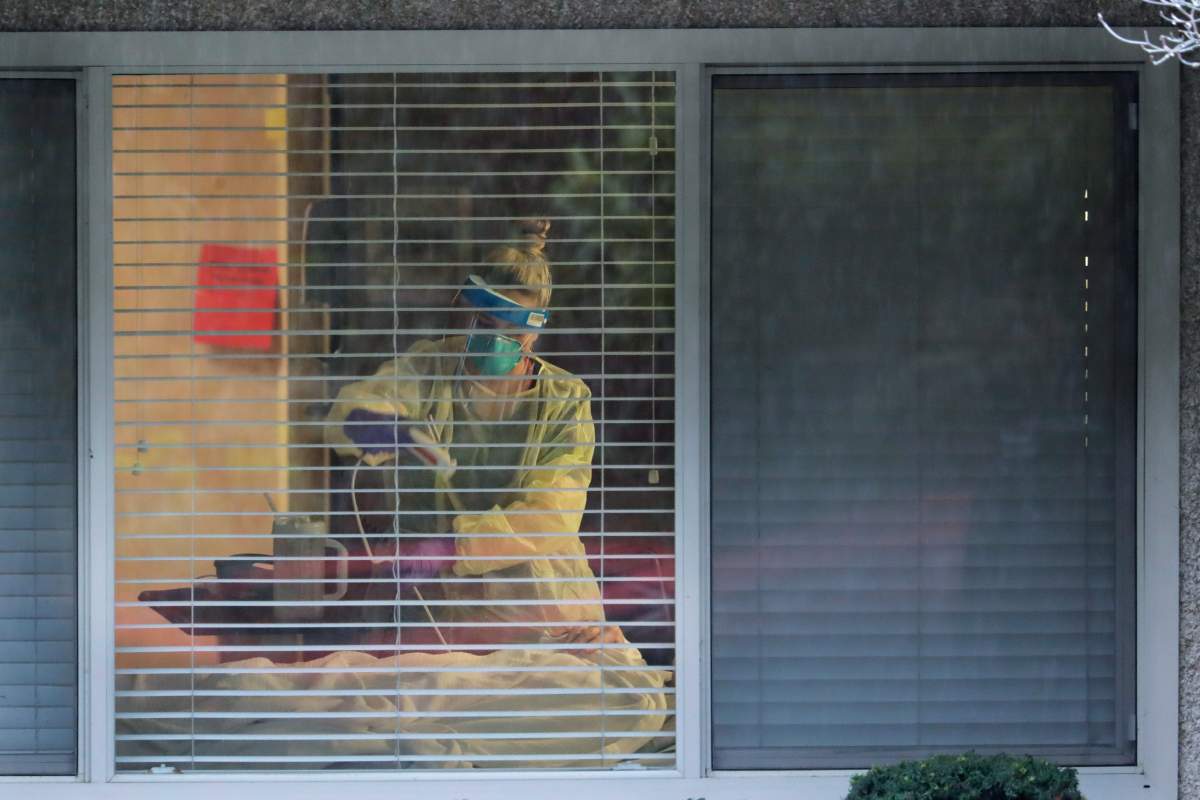 In this file photo, a nurse works in the room of a patient who has tested positive for the COVID-19.
