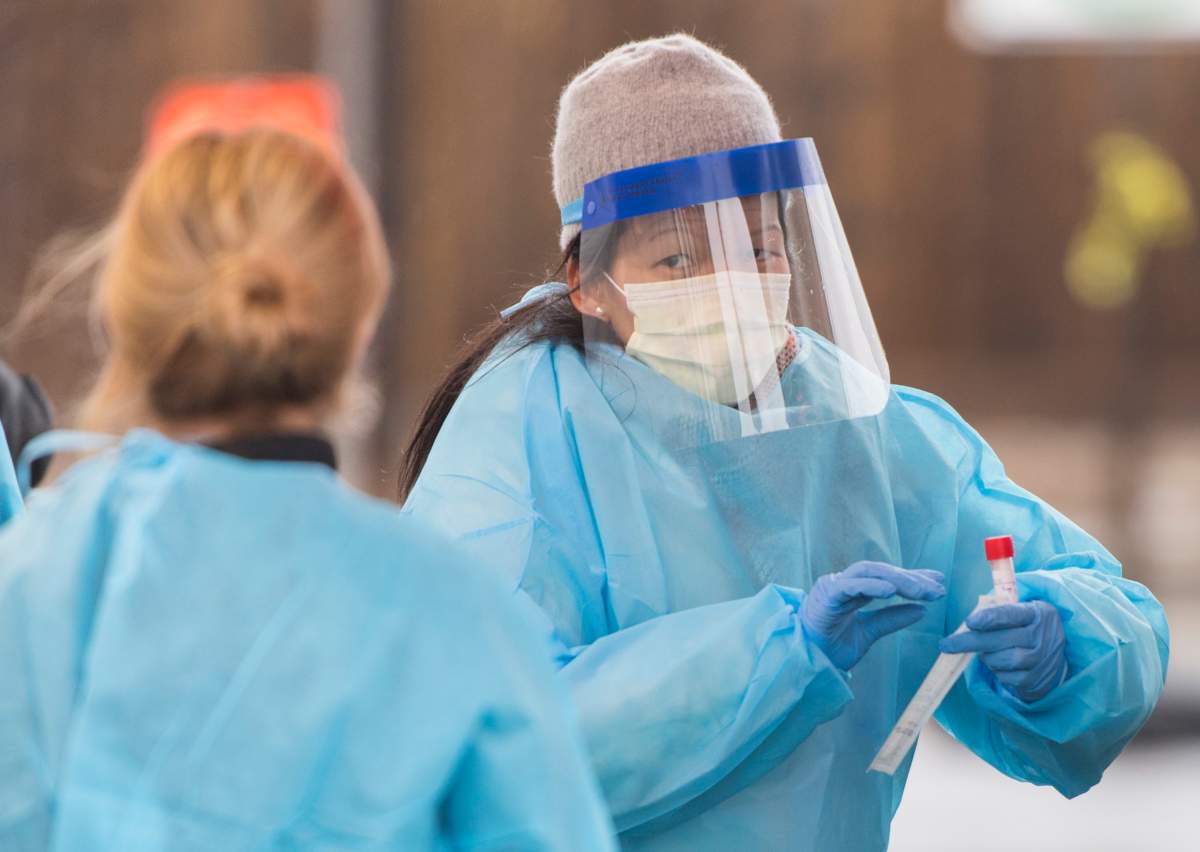 FILE: A healthcare worker prepares to issue a COVID-19 test at a drive-thru COVID-19 evaluation clinic.